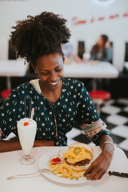 Jonge Afrikaanse Amerikaanse vrouw die in diner eet