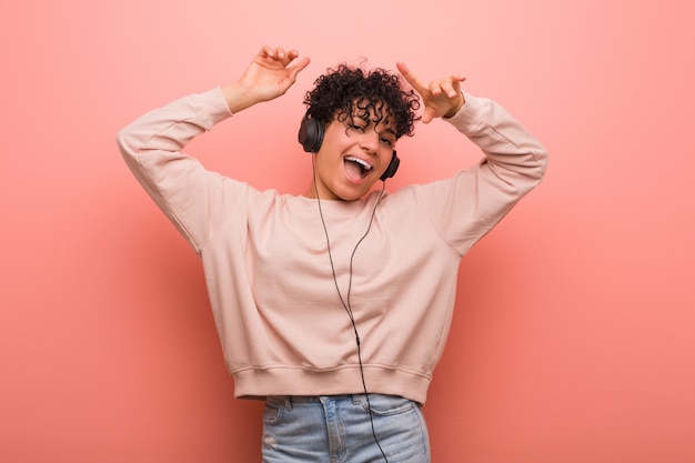 Jonge Afrikaanse Amerikaanse vrouw met een moedervlek die en aan muziek met een hoofdtelefoon dansen luisteren