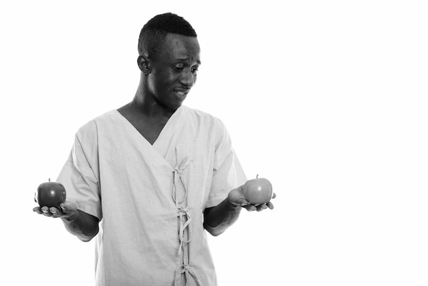 jonge Afrikaanse man als ziekenhuispatiënt geïsoleerd tegen witte muur in zwart en wit