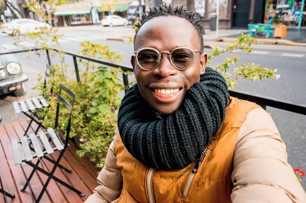 Jonge Afrikaanse man die buiten het restaurant zit, maakt een selfie terwijl hij wacht op het ontbijt