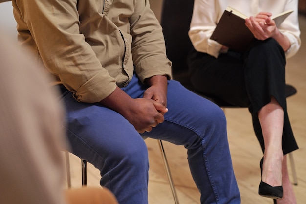 Jonge Afrikaanse man in vrijetijdskleding zittend op een stoel tijdens psychologische sessie