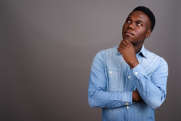 jonge Afrikaanse man met denim overhemd tegen grijze ruimte