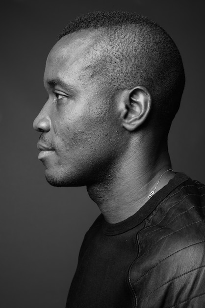 jonge Afrikaanse man met een zwart shirt met lange mouwen tegen een grijze muur. zwart en wit