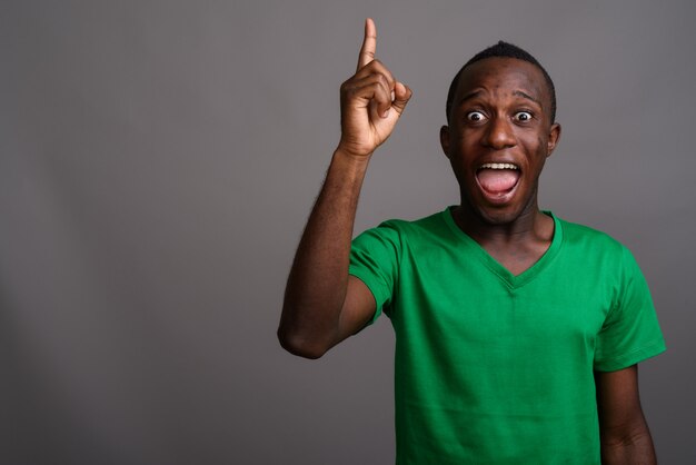 Jonge Afrikaanse man met groen shirt op grijze muur