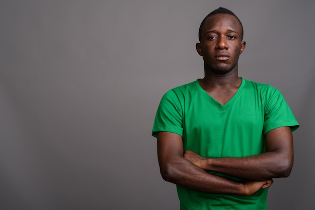 Jonge Afrikaanse man met groen shirt op grijze muur