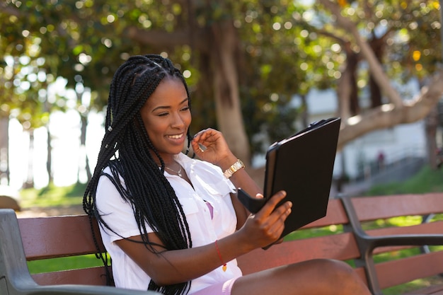 Jonge Afrikaanse student lacht en kijkt naar haar tablet.