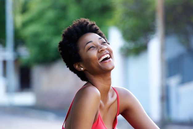 Jonge Afrikaanse vrouw buiten zitten en lachen