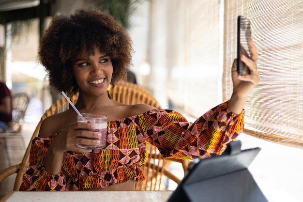 Jonge afrikaanse vrouw die lacht voor sociale media in restaurant