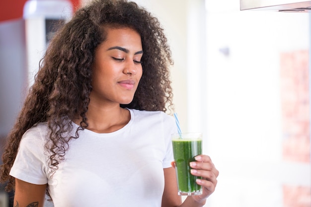 Jonge Afrikaanse vrouw geniet van gezonde vegetarische smoothie voor gewichtsverlies en detox