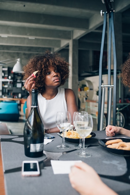 Jonge Afrikaanse vrouw het drinken wijn in modern restaurant met vrienden