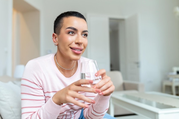 Jonge Afrikaanse vrouw in vrijetijdskleding drinkwater uit glas