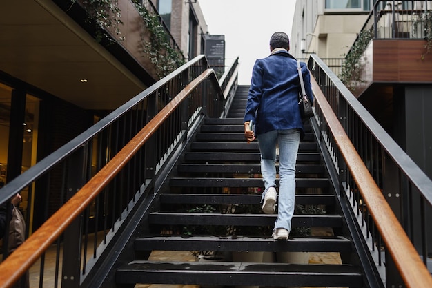 Jonge afrikaanse vrouw met kort haar draagt trendy outfit die de trap op gaat