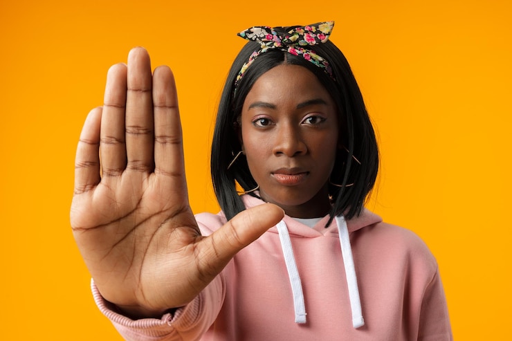 Foto jonge afrikaanse vrouw op gele achtergrond doet stopteken met de palm van de hand