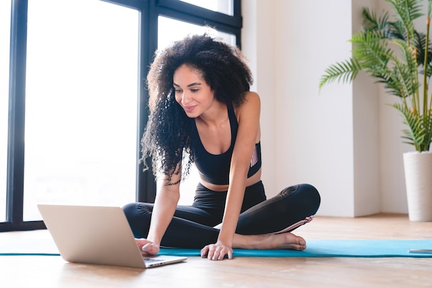 Foto jonge afrikaanse vrouwelijke atleet sportvrouw op zoek naar sport online les fitness tutorial leren video op laptop voor de training trainen doen lichamelijke oefeningen