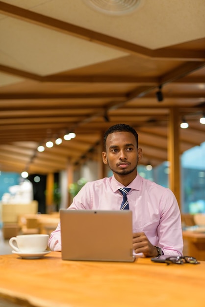 Jonge Afrikaanse zakenman in coffeeshop met behulp van laptopcomputer