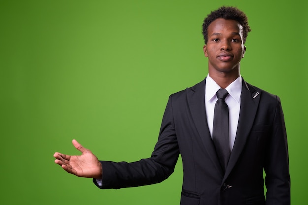 Jonge Afrikaanse zakenman tegen groene muur