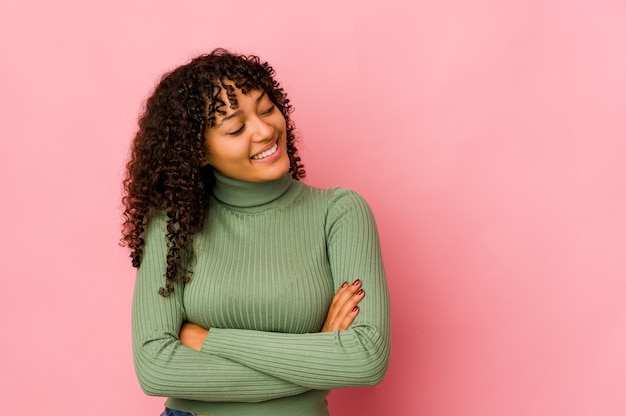 Jonge afro-amerikaanse afro vrouw geïsoleerd glimlachend zelfverzekerd met gekruiste armen.