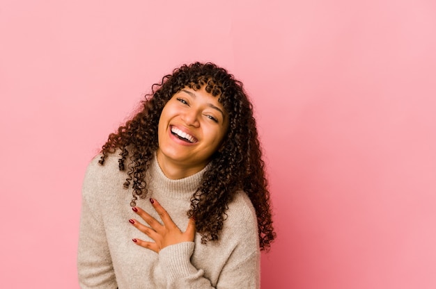 Jonge afro-amerikaanse afro vrouw geïsoleerd lacht hardop hand op de borst te houden.