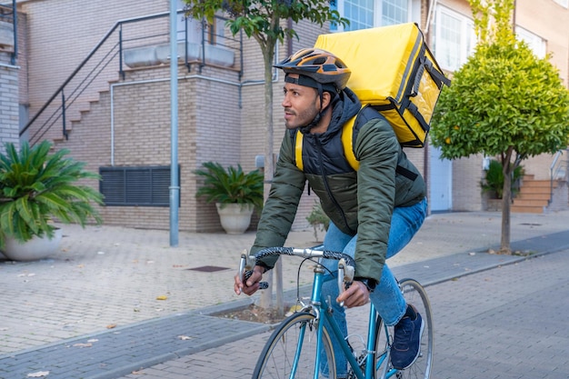 Jonge afro-amerikaanse bezorger rijden op fiets zwarte koerier die eten en drinken bezorgt in de stad