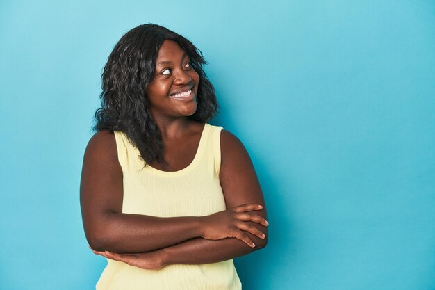 Jonge Afro-Amerikaanse curvy vrouw glimlachend zelfverzekerd met gekruiste armen