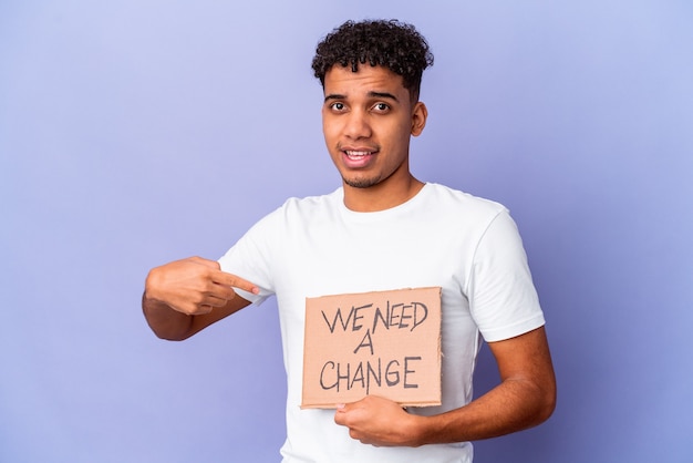 Jonge Afro-Amerikaanse gekrulde man geïsoleerd met een we hebben een kartonnen persoon nodig die met de hand wijst naar de kopie ruimte van een overhemd, trots en zelfverzekerd