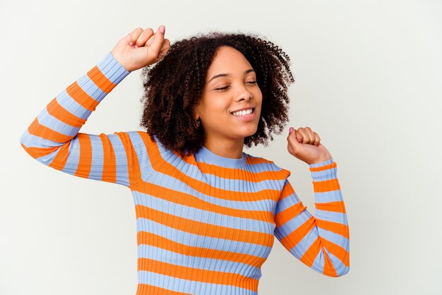 Jonge Afro-Amerikaanse halfbloed geïsoleerde vrouw viert een speciale dag, springt en heft de armen op met energie.