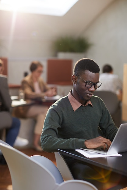 Jonge Afro-Amerikaanse man aan het werk in Cafe