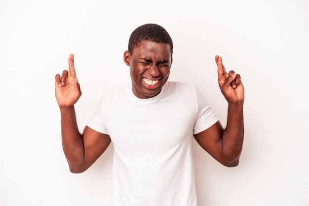 Jonge Afro-Amerikaanse man geïsoleerd op een witte achtergrond die vingers kruist om geluk te hebben