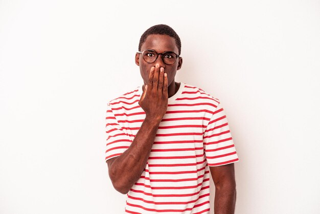 Foto jonge afro-amerikaanse man geïsoleerd op een witte achtergrond geschokt die mond bedekt met handen die bang zijn om iets nieuws te ontdekken