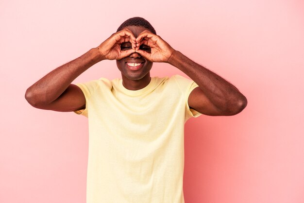 Jonge Afro-Amerikaanse man geïsoleerd op roze achtergrond met goed teken boven de ogen