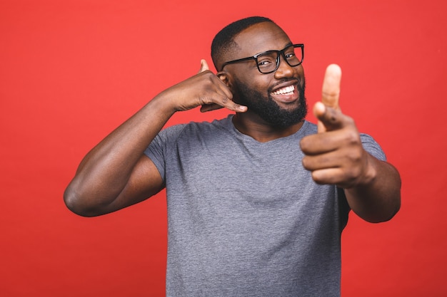 Jonge Afro-Amerikaanse man glimlachend en praten over het telefoongebaar en wijst naar jou