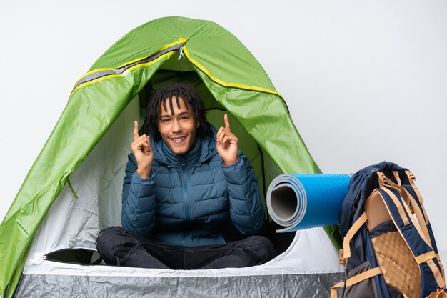 Jonge afro-amerikaanse man in een camping groene tent die een geweldig idee