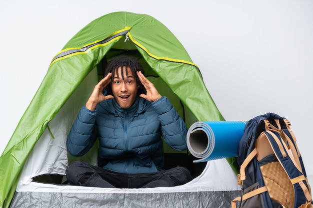 Jonge afro-amerikaanse man in een camping groene tent met verrassing expressie