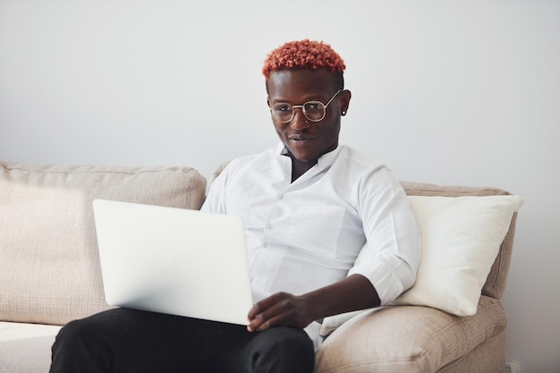 Jonge Afro-Amerikaanse man in formele kleding binnenshuis met laptop in handen