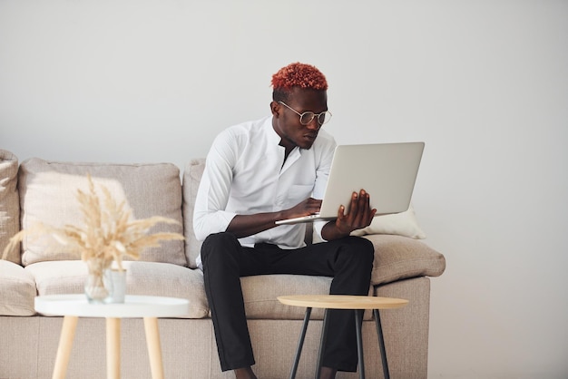 Jonge Afro-Amerikaanse man in formele kleding binnenshuis met laptop in handen