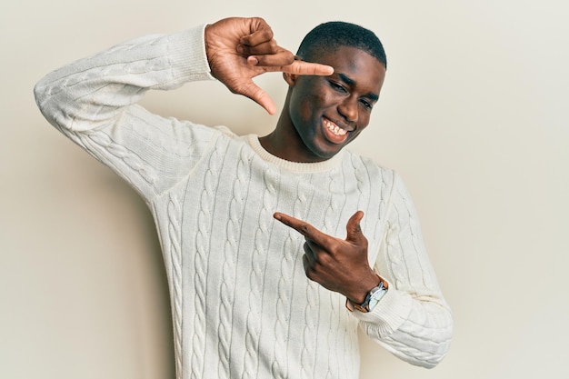 Jonge afro-amerikaanse man met casual kleding glimlachend frame maken met handen en vingers met blij gezicht creativiteit en fotografie concept