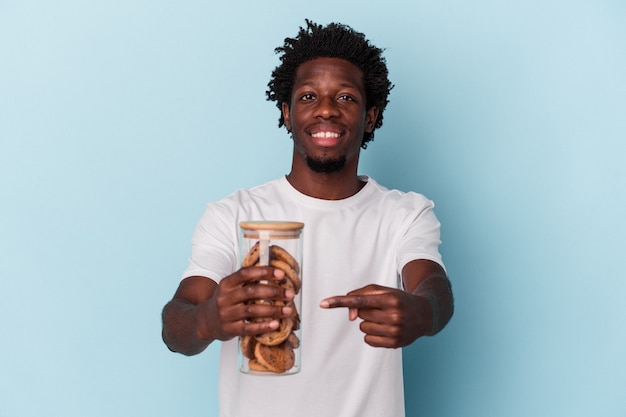 Jonge Afro-Amerikaanse man met chocoladeschilfers cookies geïsoleerd op blauwe achtergrond