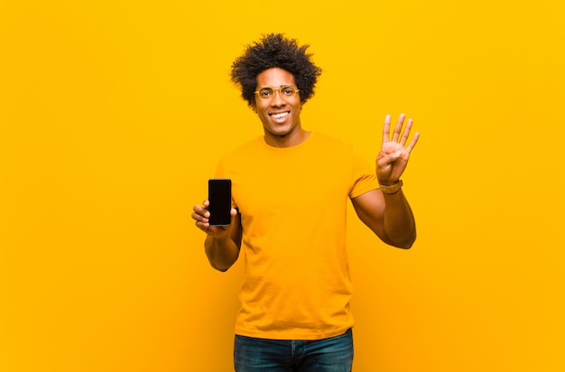 Jonge afro-amerikaanse man met een slimme telefoon tegen oranje bac