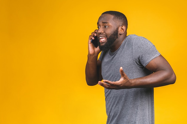 Jonge Afro-Amerikaanse man met smartphone benadrukt, geschokt met schaamte en verrassingsgezicht, boos en gefrustreerd. Angst en boos op fouten.