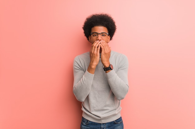 Jonge Afro-Amerikaanse man over een roze muur erg bang en bang verborgen