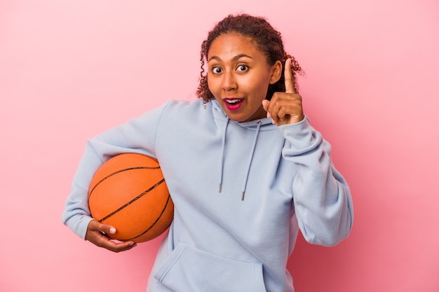 Jonge Afro-Amerikaanse man spelen basketbal geïsoleerd op roze achtergrond met een idee, inspiratie concept.