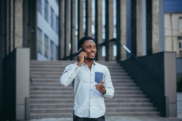 Jonge Afro-Amerikaanse mannelijke student met plezier praten op mobiele telefoon