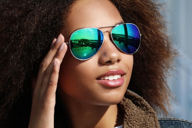 Jonge Afro-Amerikaanse meid in zonnebril poseren buitenshuis Casual gekleed met kort volumineus haar