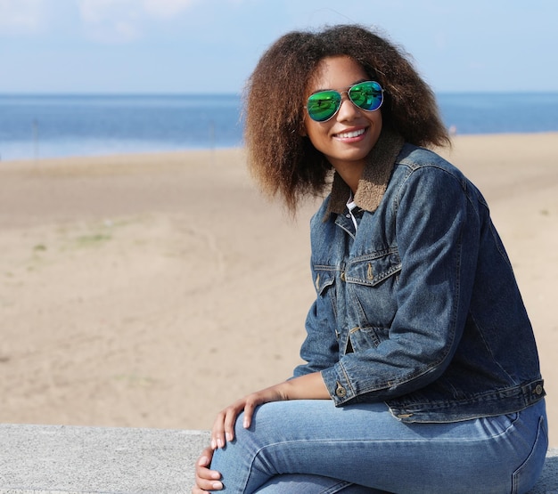 Jonge Afro-Amerikaanse meid in zonnebril poseren buitenshuis Casual gekleed met kort volumineus haar