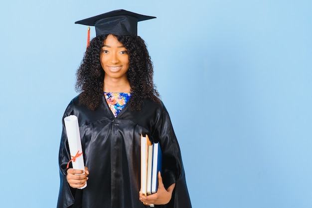 Jonge Afro-Amerikaanse student in bachelor gewaad op kleur achtergrond