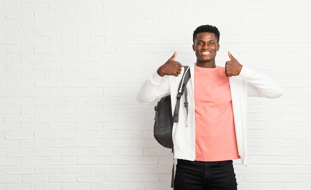 Jonge afro Amerikaanse studente die duimen op gebaar en het glimlachen geeft omdat succes heeft gehad