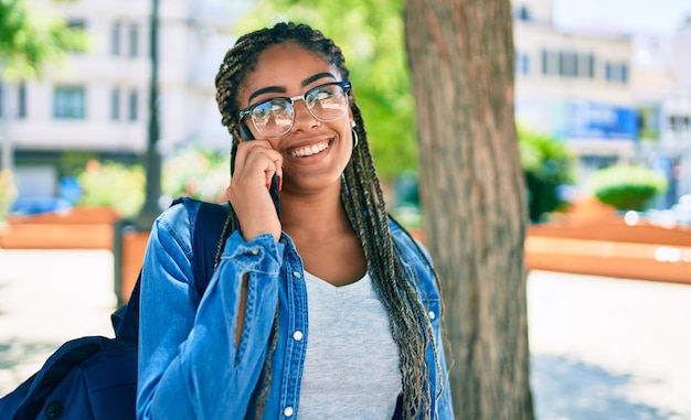 Jonge afro-amerikaanse studentenvrouw die lacht gelukkig sprekend op smartphone op de universiteitscampus