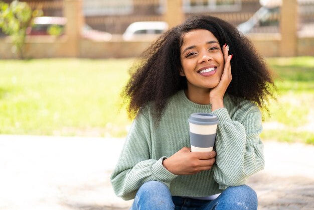 Jonge Afro-Amerikaanse vrouw buiten met een koffie om mee te nemen