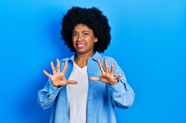 Jonge afro-amerikaanse vrouw die casual kleding draagt, bang en doodsbang van angstuitdrukking stop gebaar met handen schreeuwend in shock paniek concept