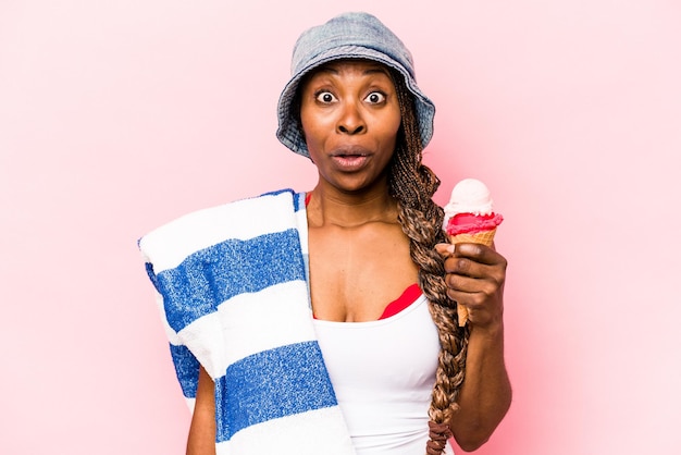 Jonge Afro-Amerikaanse vrouw die naar het strand gaat met een ijsje geïsoleerd op roze achtergrond